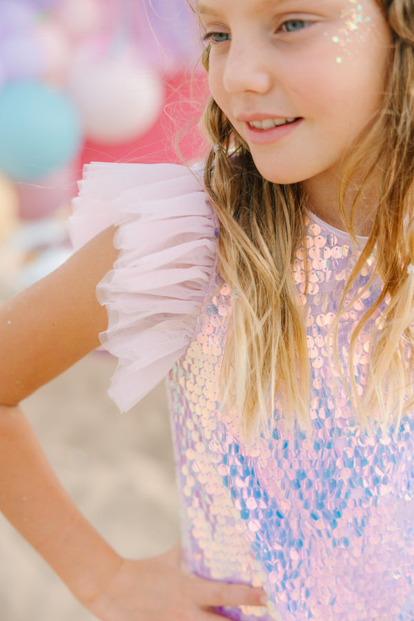 Young girl wearing a sequin dress with a blurred colorful background