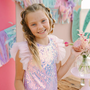 Young girl in a sequined dress holding flowers in a colorful setting