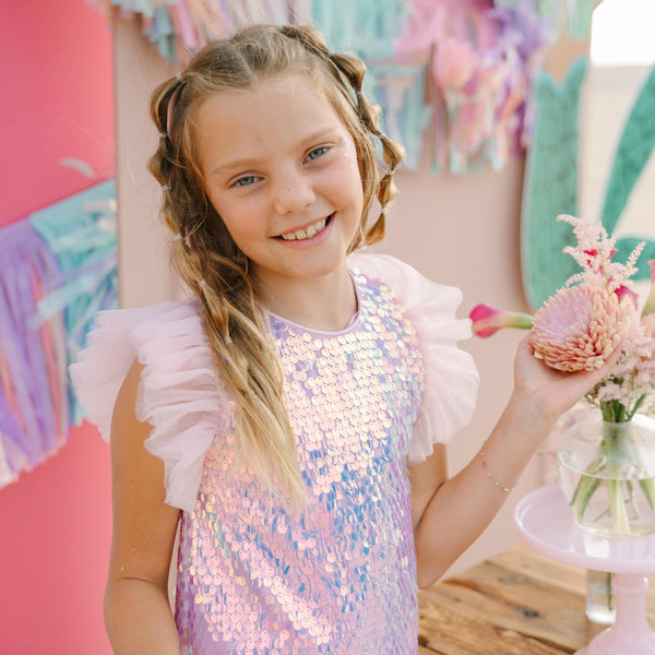 Young girl in a sequined dress holding flowers in a colorful setting
