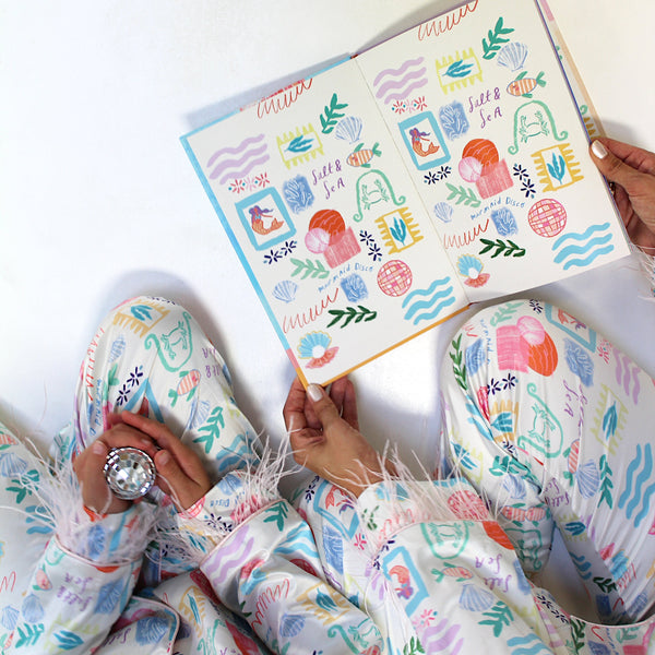 Person wearing a colorful pajama set holding a decorated notebook.