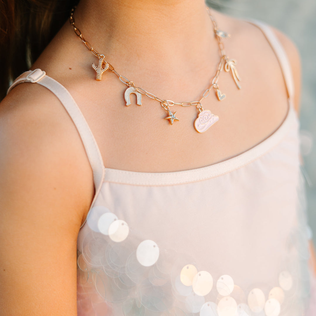Close-up of a young girl wearing a delicate necklace with heart-shaped pendants against a blurred background.