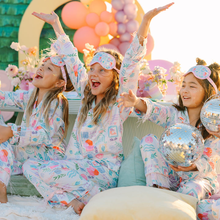 Children in pajamas with decorative headbands and balloons, celebrating a birthday.