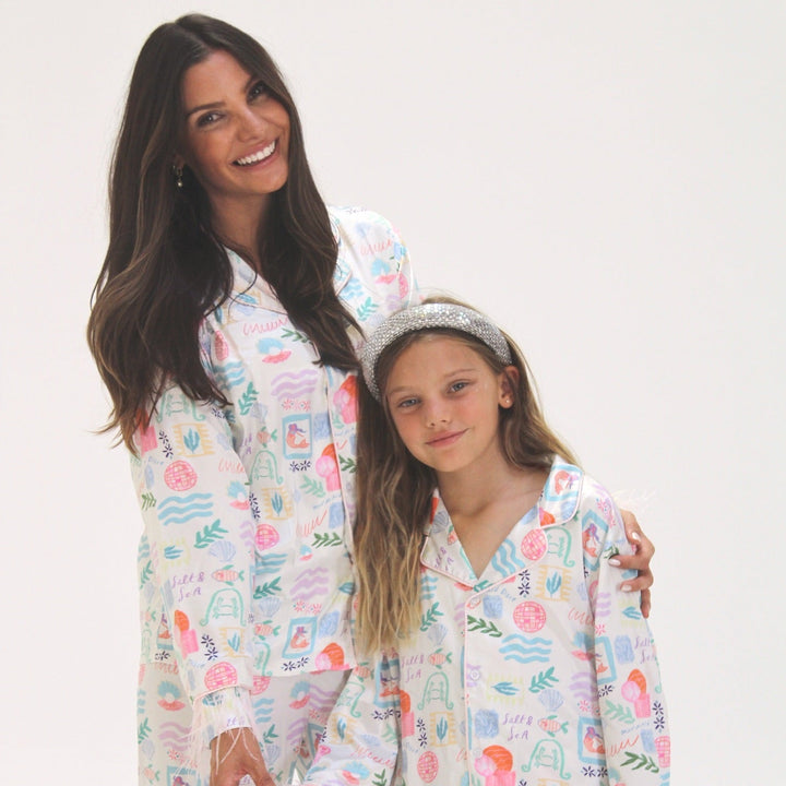 Mom and daughter wearing matching pajamas against a white background