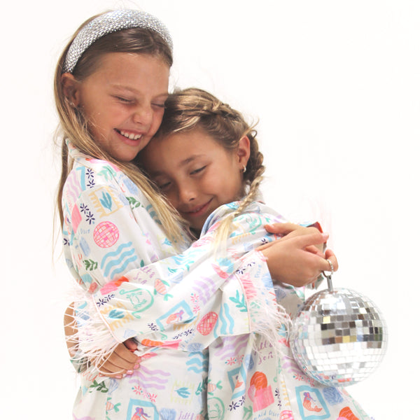 Two children in matching pajamas with a disco ball, on a white background