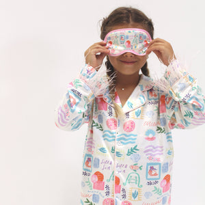 Child wearing a colorful pajama and matching sleep mask on a white background