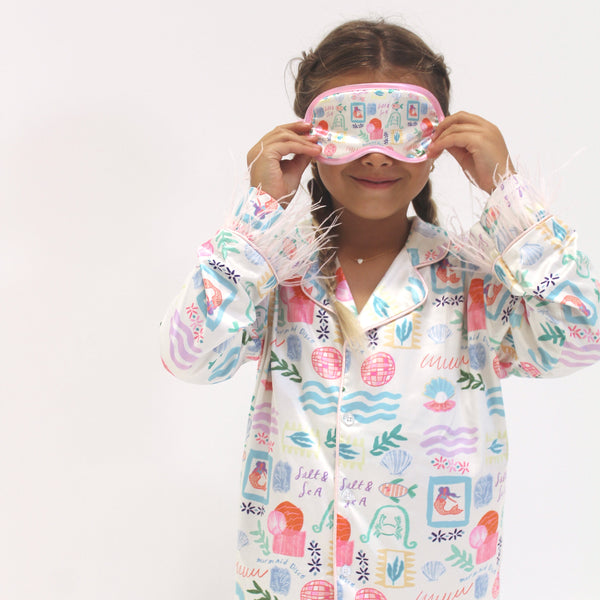 Child wearing a colorful pajama and matching sleep mask on a white background