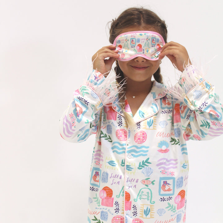 Child wearing a colorful pajama and matching sleep mask on a white background