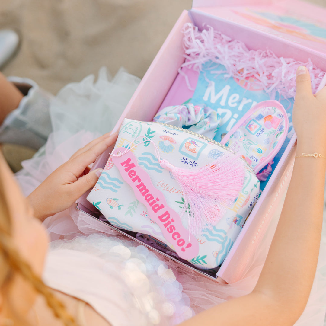 Person holding a box of Mermaid Disco! products on a beach.