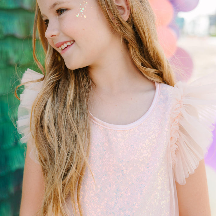 Young girl with fairy wings and face paint against a colorful balloon background